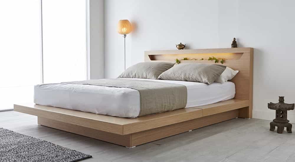 Modern wooden platform bed with neutral bedding and built-in headboard lighting in minimalist bedroom
