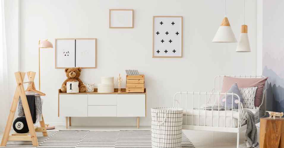 Modern kids bedroom with white bed, pastel pillows, teddy bear, wooden furniture, and minimalist decor